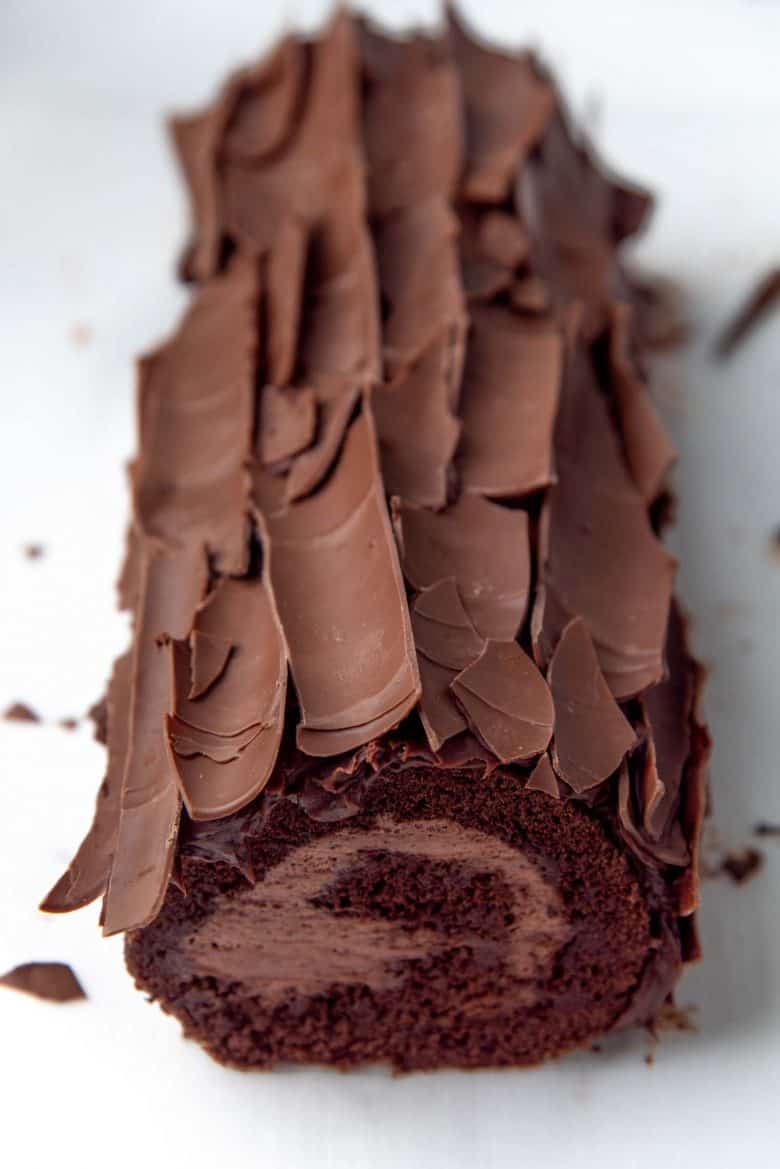 Chocolate swiss roll cake completely covered by chocolate shards