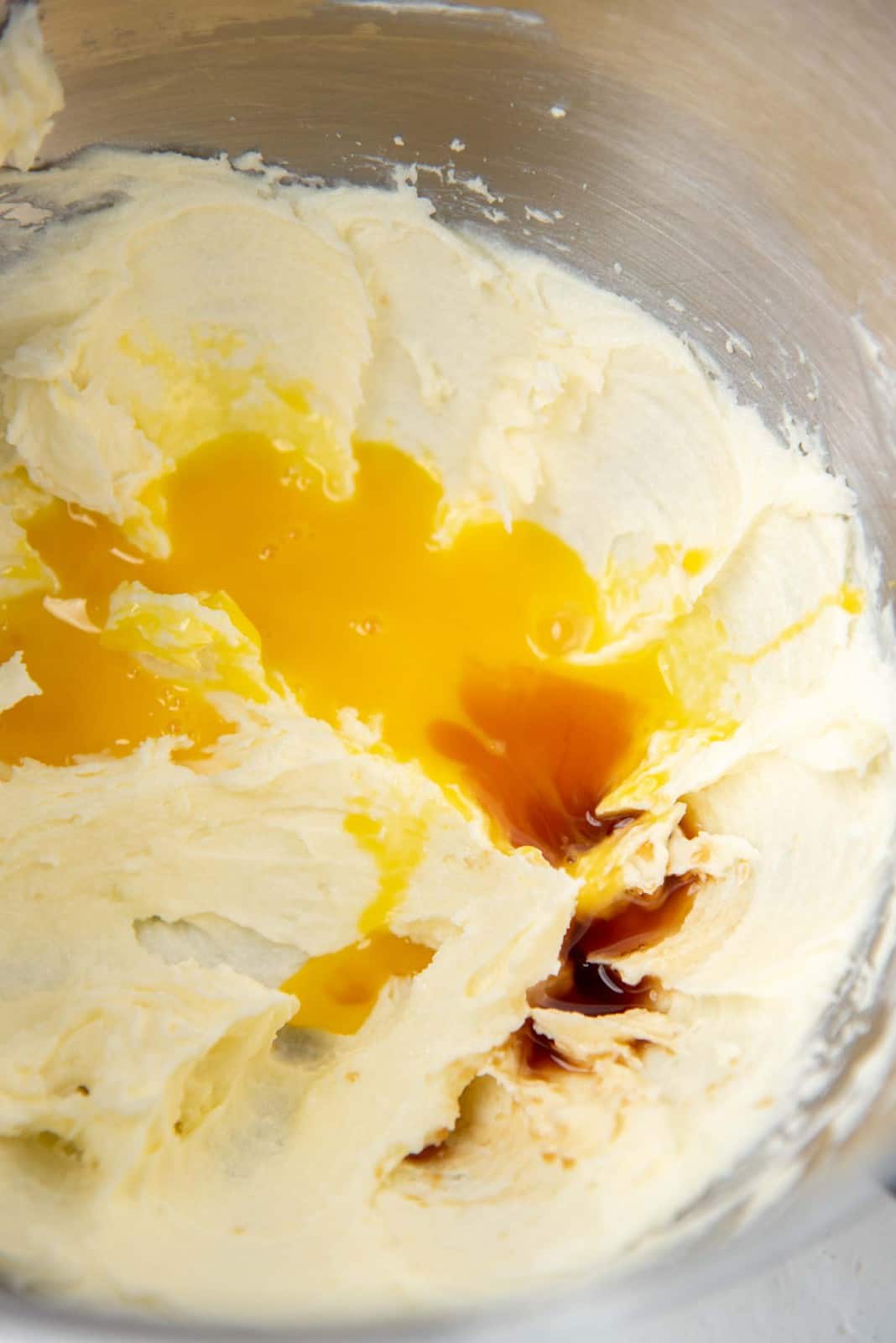 Adding the egg yolks and vanilla to the creamed butter and sugar mixture