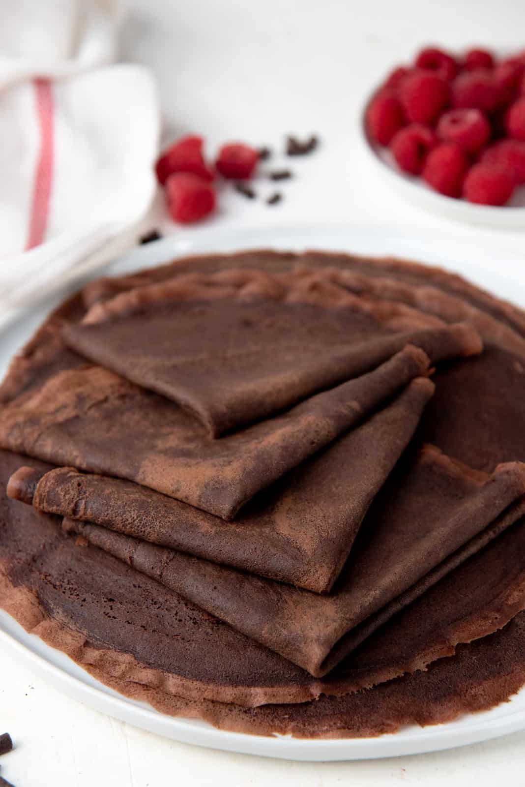 Folded chocolate crepes close up on a white plate