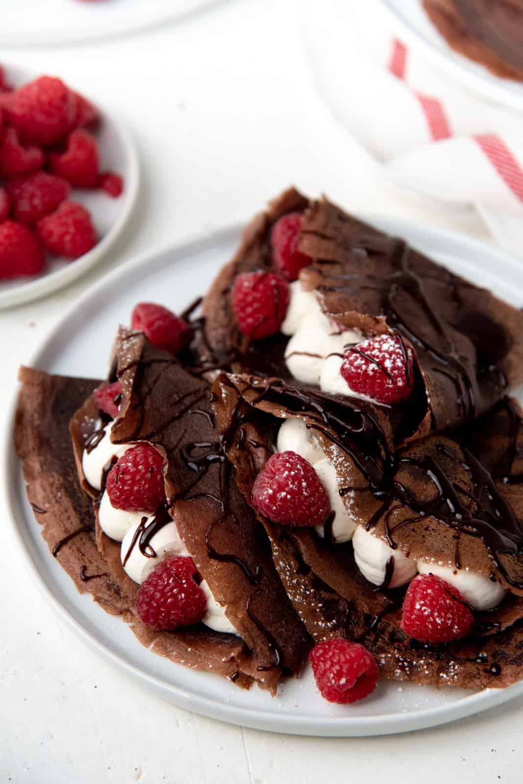 Chocolate Crepes folded over and filled with cream and raspberries