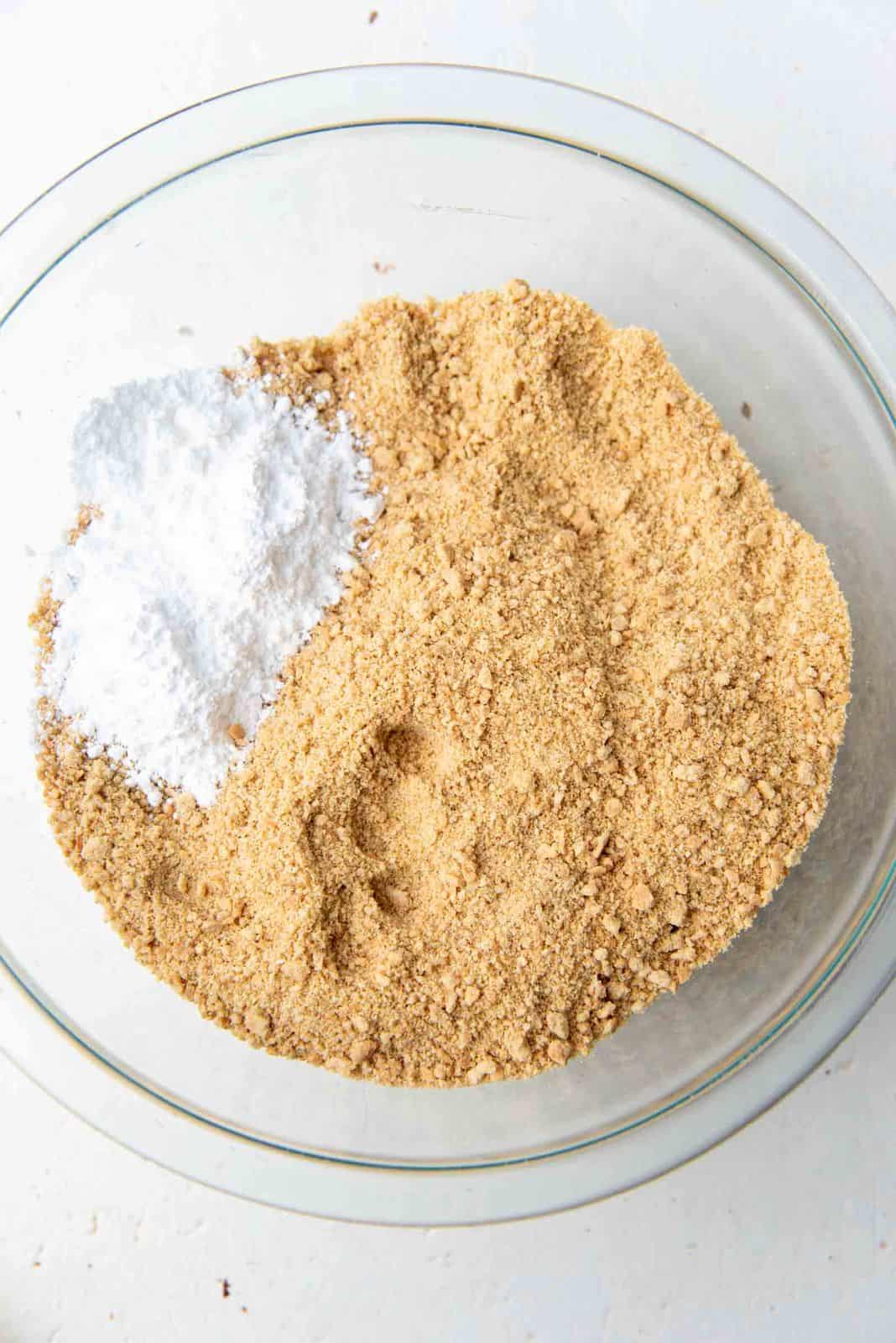 Crushed graham cracker crumbs and sugar in a large glass bowl.
