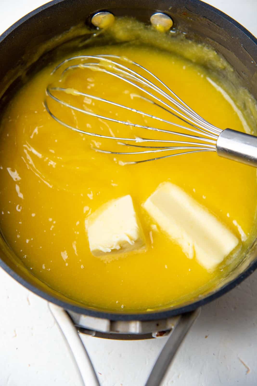 Thickened lemon curd in a saucepan after adding butter and cooking with eggs.