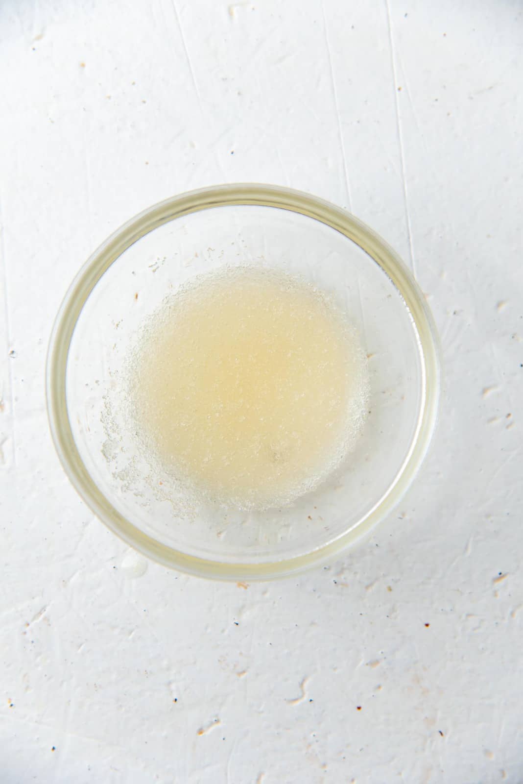 Bloomed gelatin in a small glass bowl.