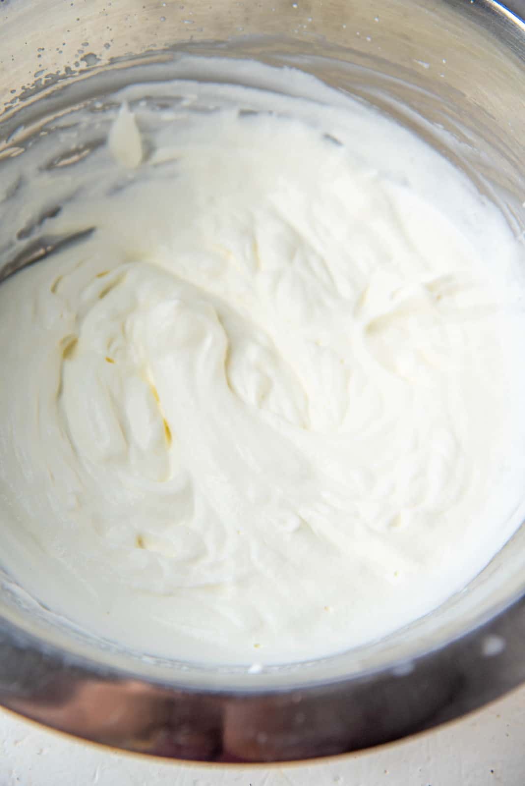 Stainless steel bowl filled with smooth, softly whipped cream.