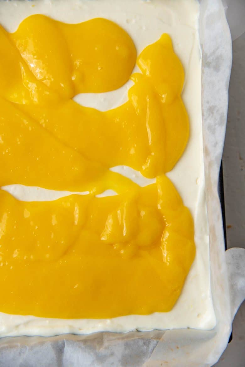 The cooled down lemon curd topping spread on top of the cheesecake layer