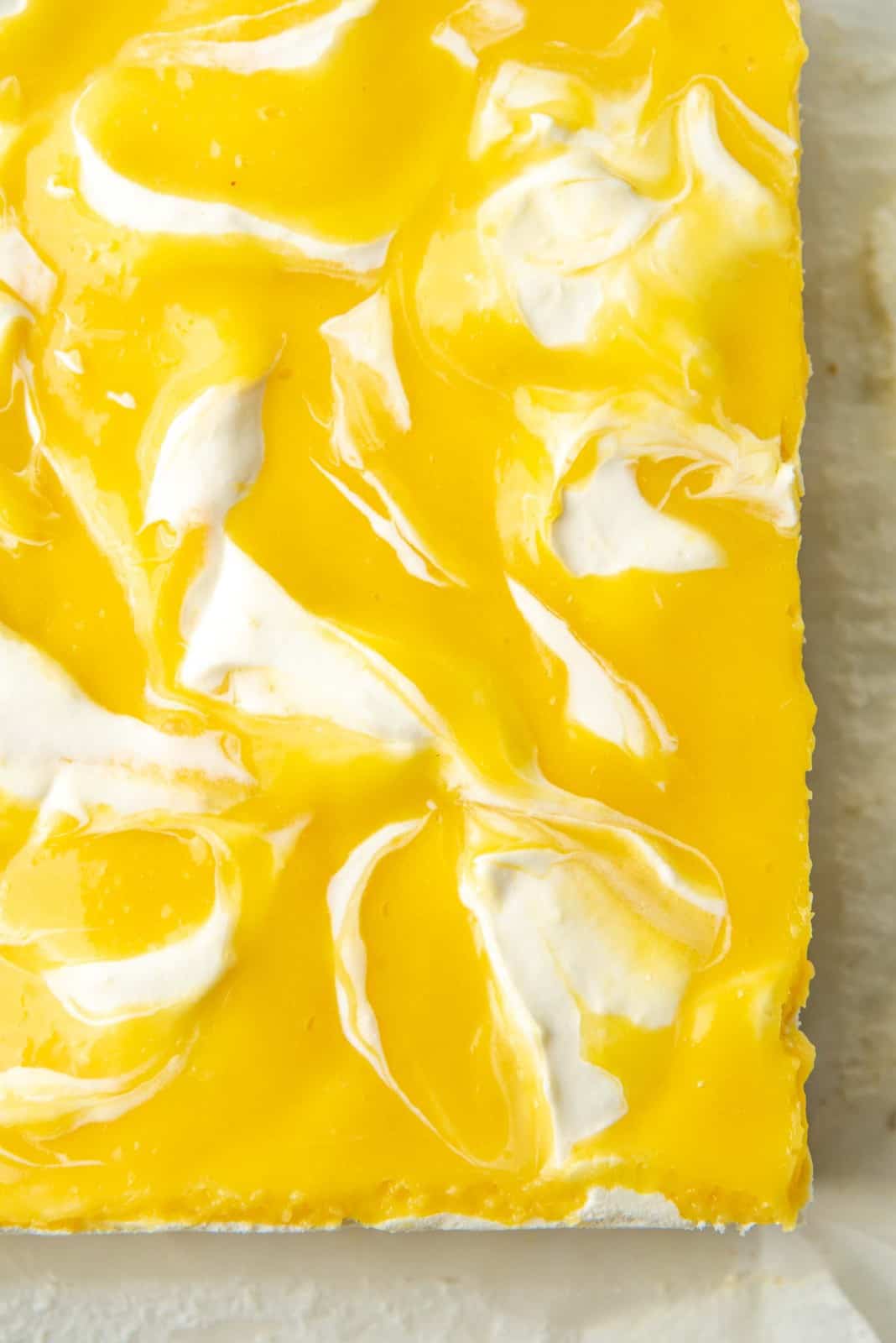 Vibrant yellow and white topping on the no bake lemon cheeseckae bar after it has set.
