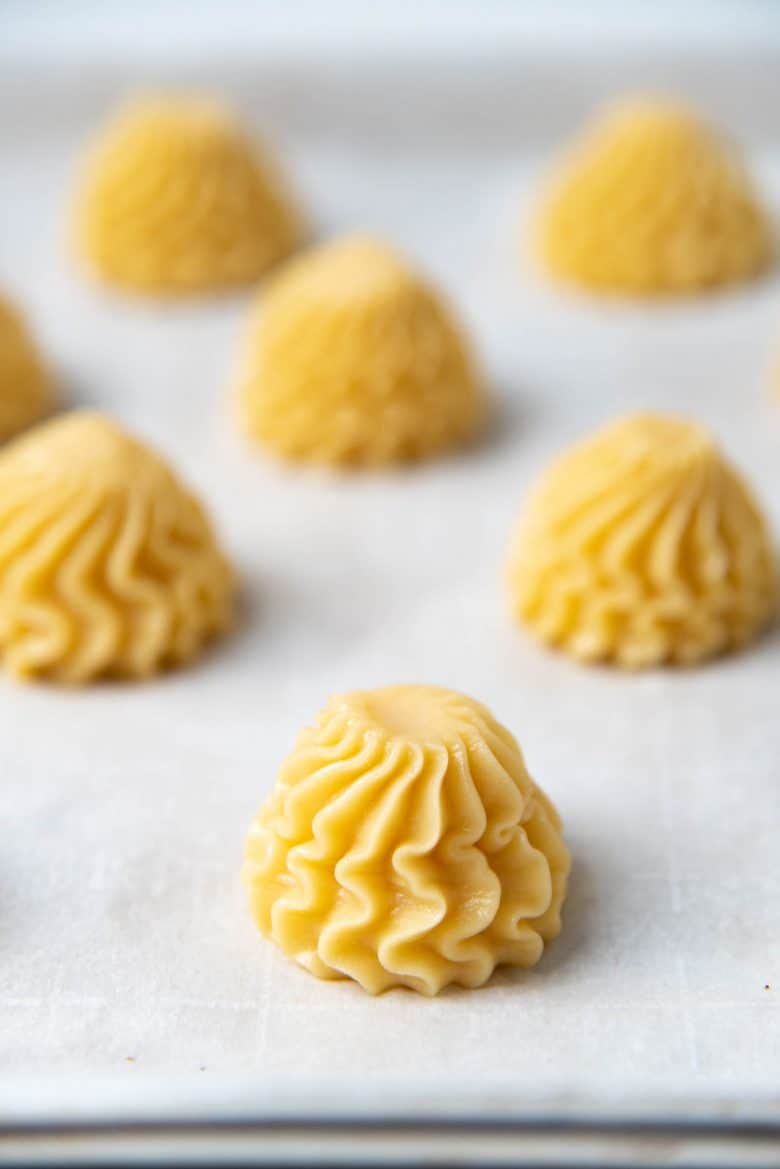 Choux pastry mounds with dampened tips before baking