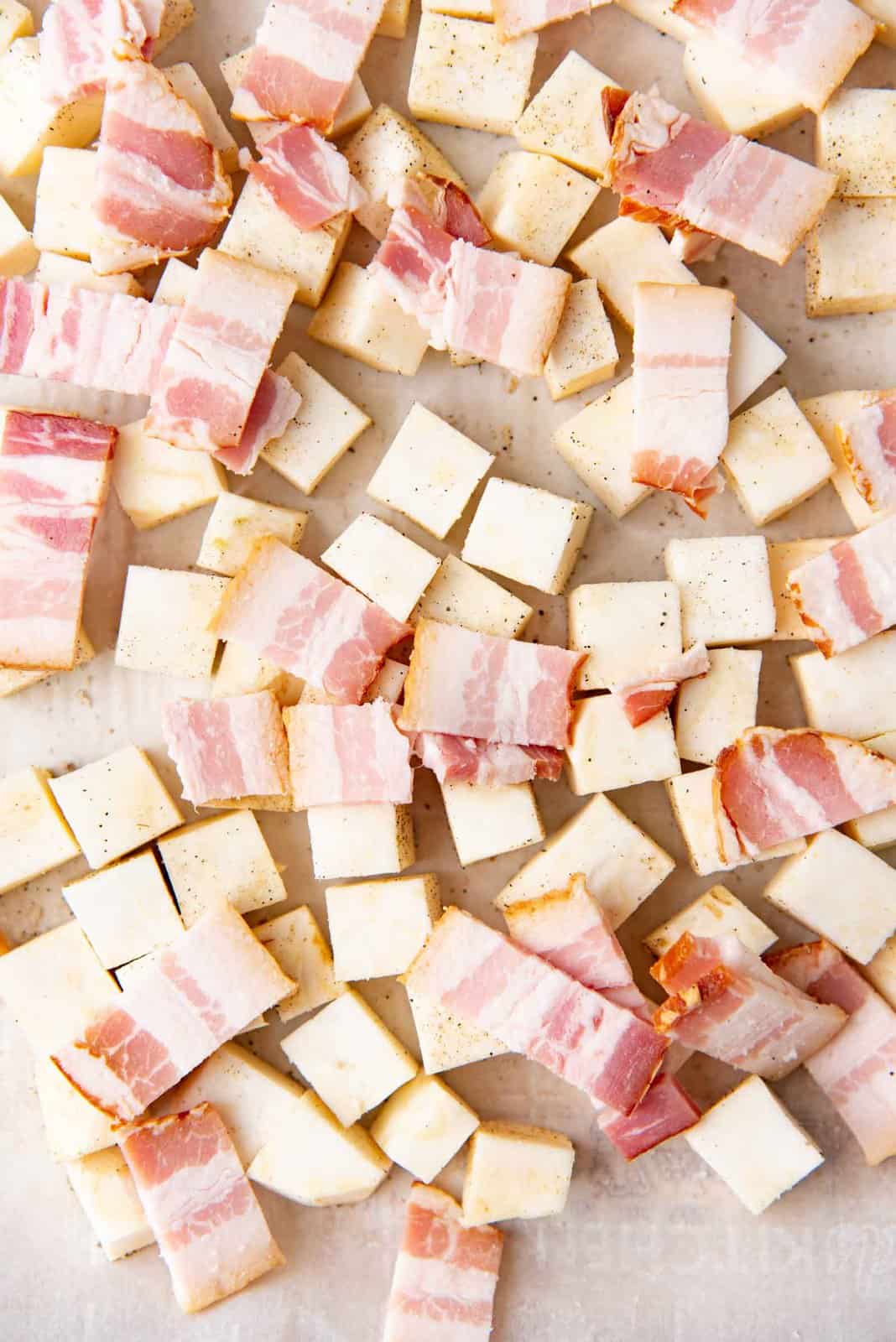 Cubed celeriac and bacon on a baking sheet.