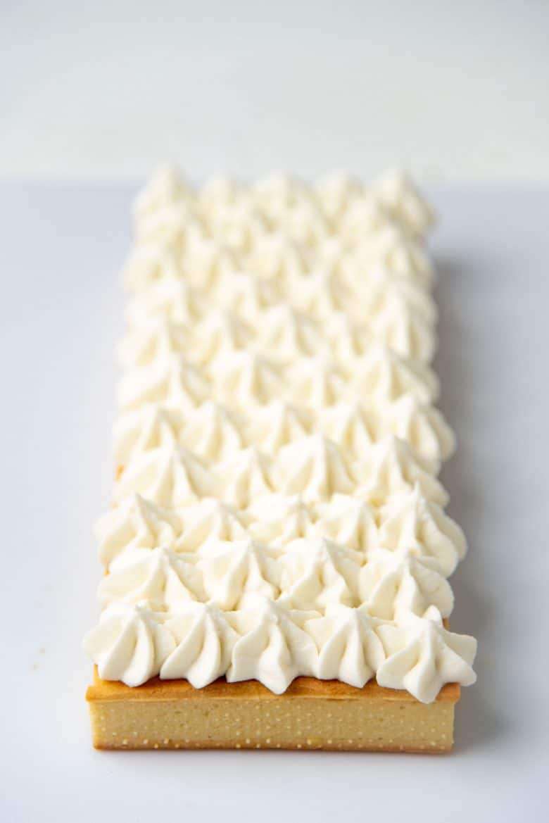 Whipped coconut cream piped on top of the pineapple tart