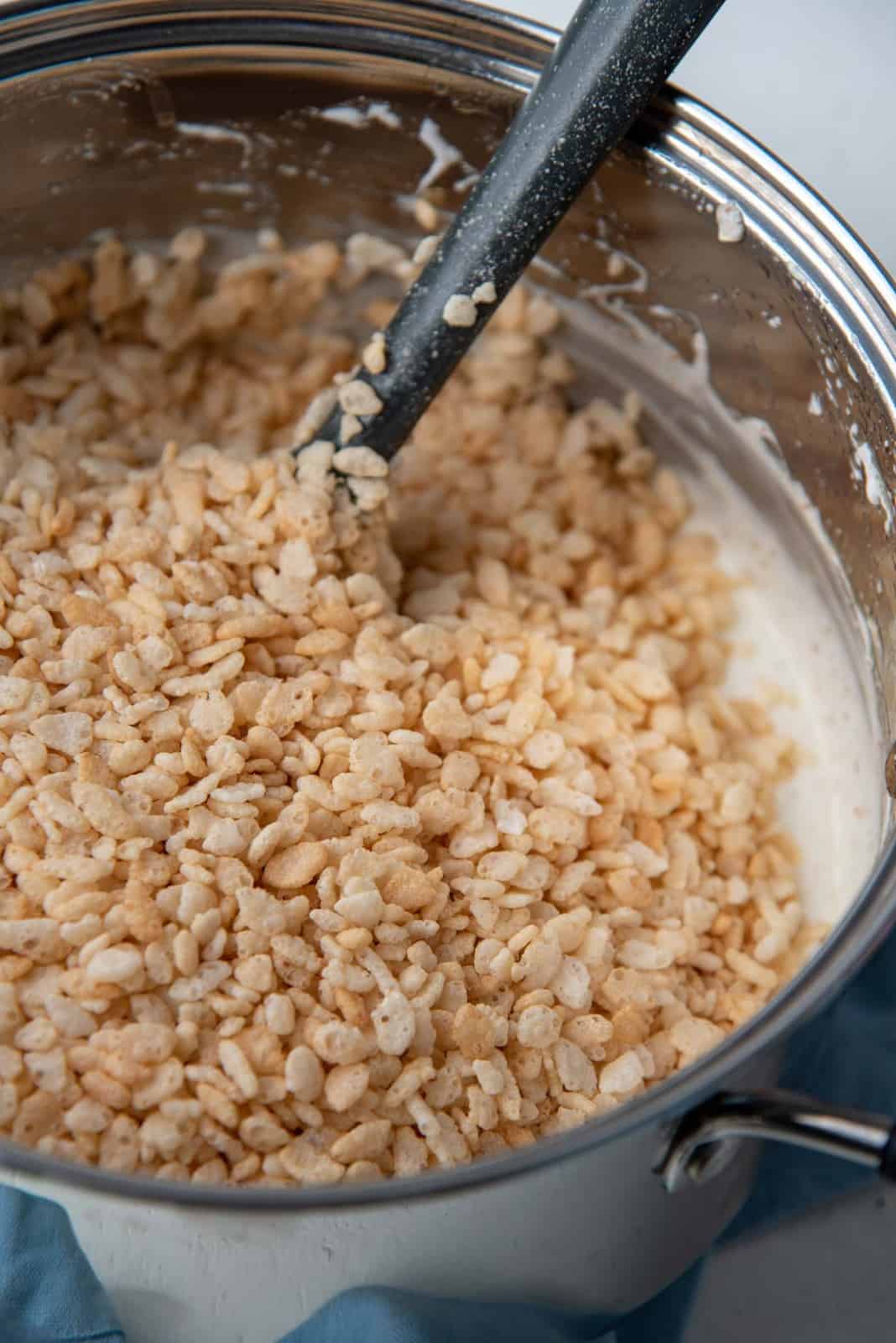 Adding the rice krispies into the melted marshmallow and butter pot