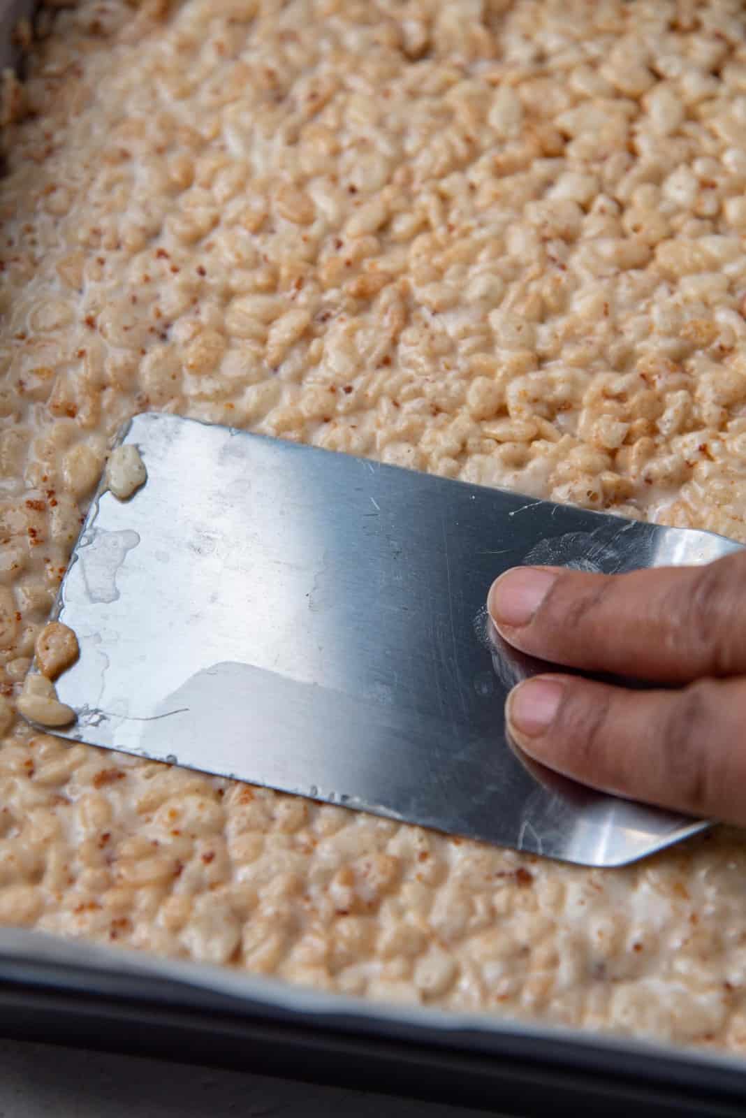 Using a flat spatula to smooth the mixture and press it gently into the pan