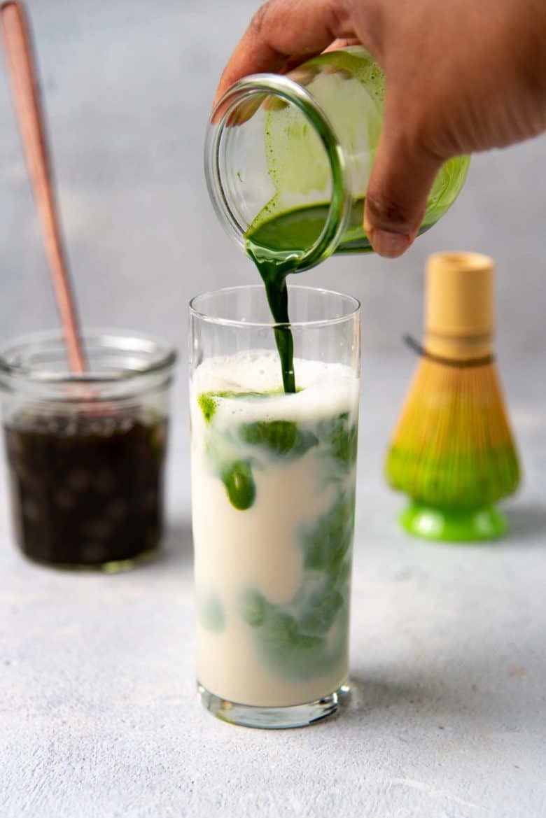 Pouring the matcha into the milk, with the ice creating swirls