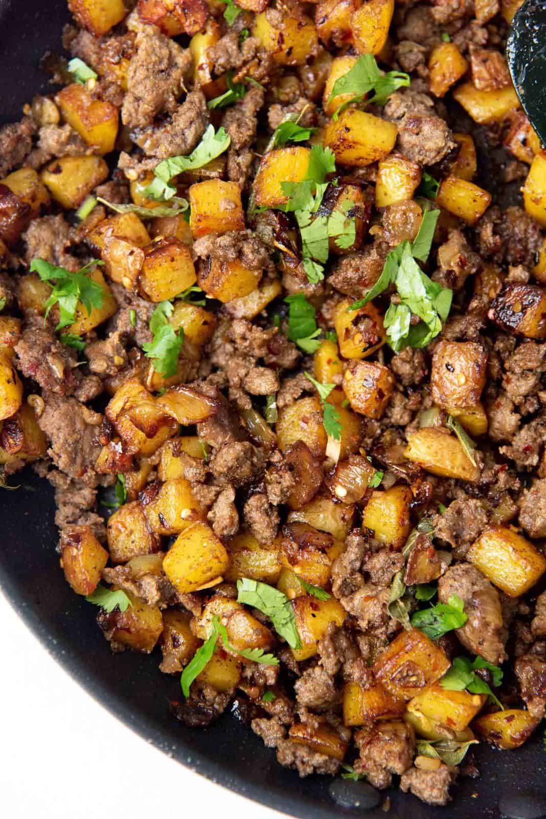 Curried potato hash with ground beef in a skillet