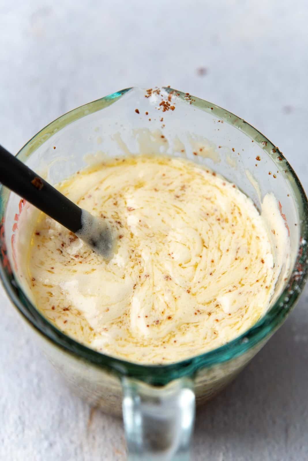 Some of the egg batter mixed with the butter in a jug