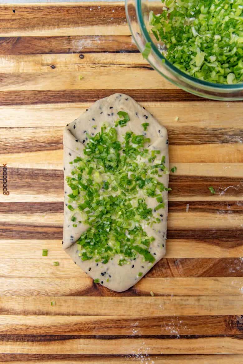 Chopped scallions sprinkled over the surface of the folded piece of dough