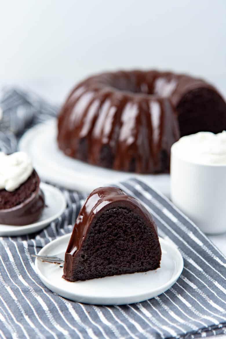 A slice of chocolate bundt cake on a small white plate.