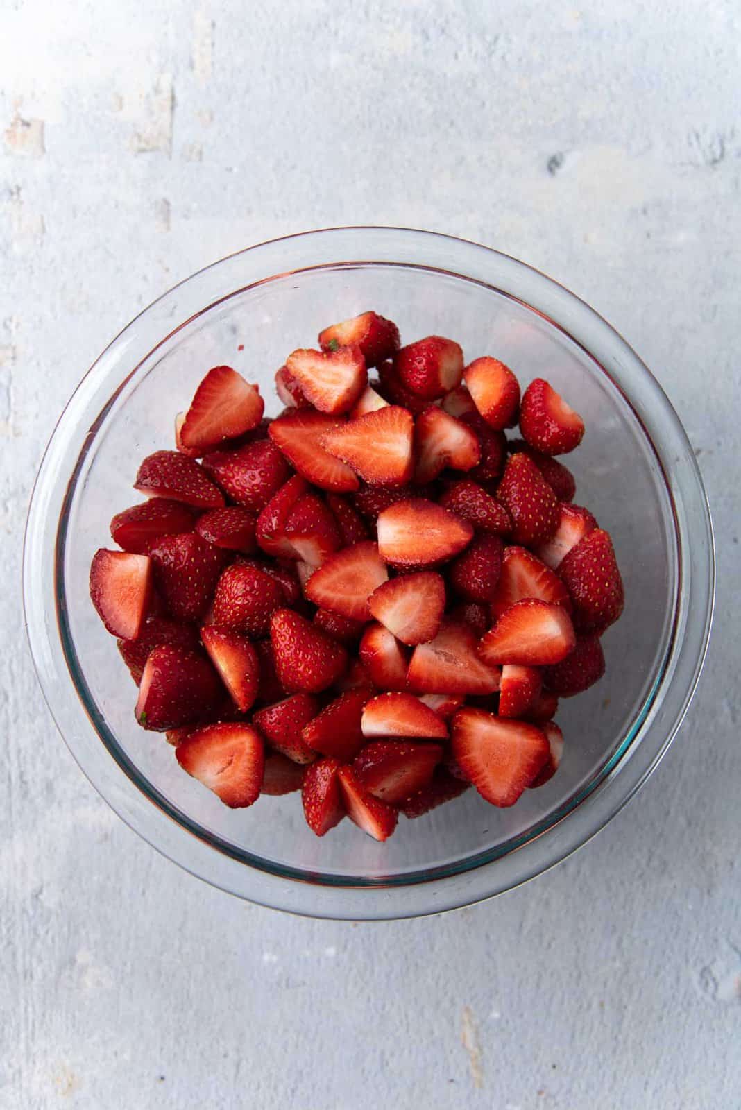Cut up strawberries in a glass bowl.