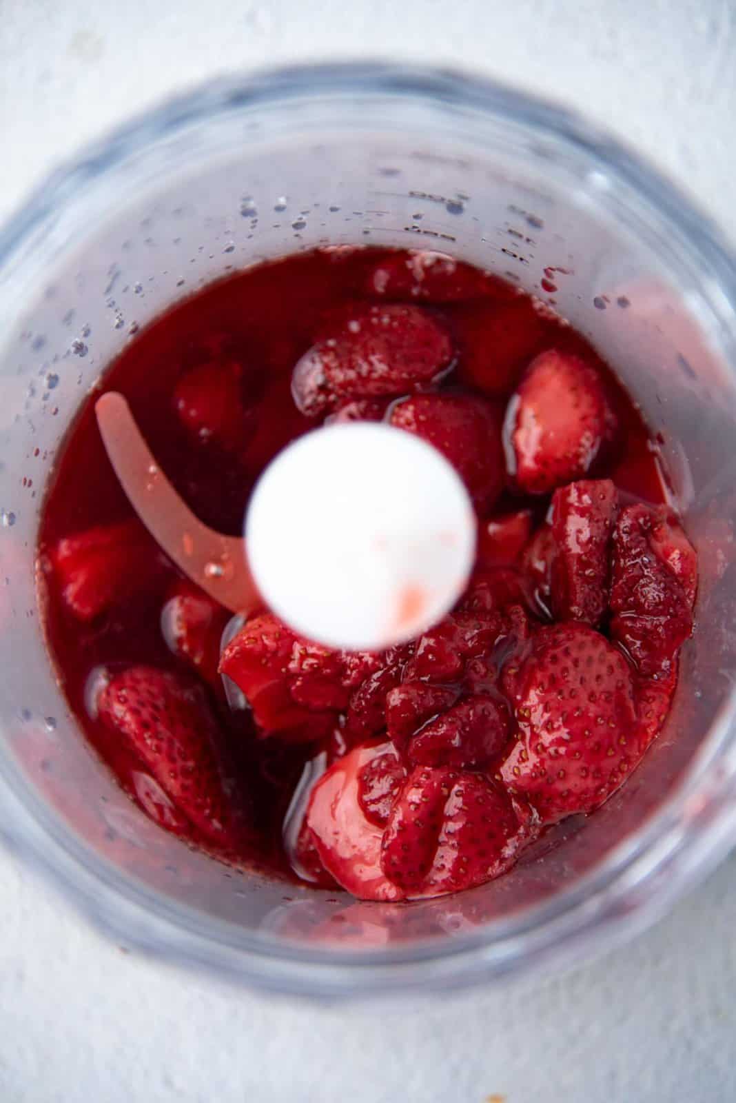 Roasted strawberries and syrup in a small blender.