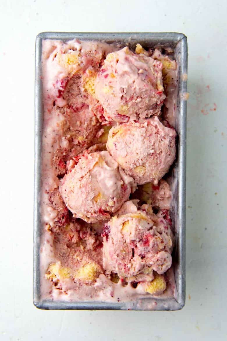 An overhead view of the strawberry shortcake ice cream, with 4 scoops on top of the rest of the ice cream. 