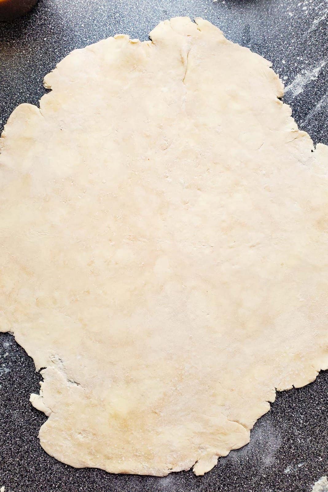 The pie crust rolled out on a work surface.