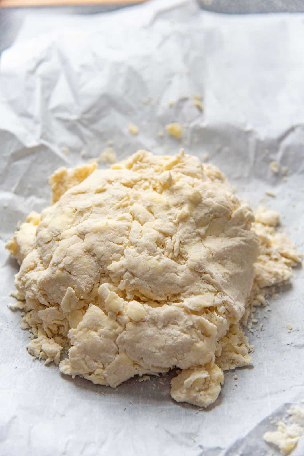 The dough placed on a parchment paper, with large clumps just help together.
