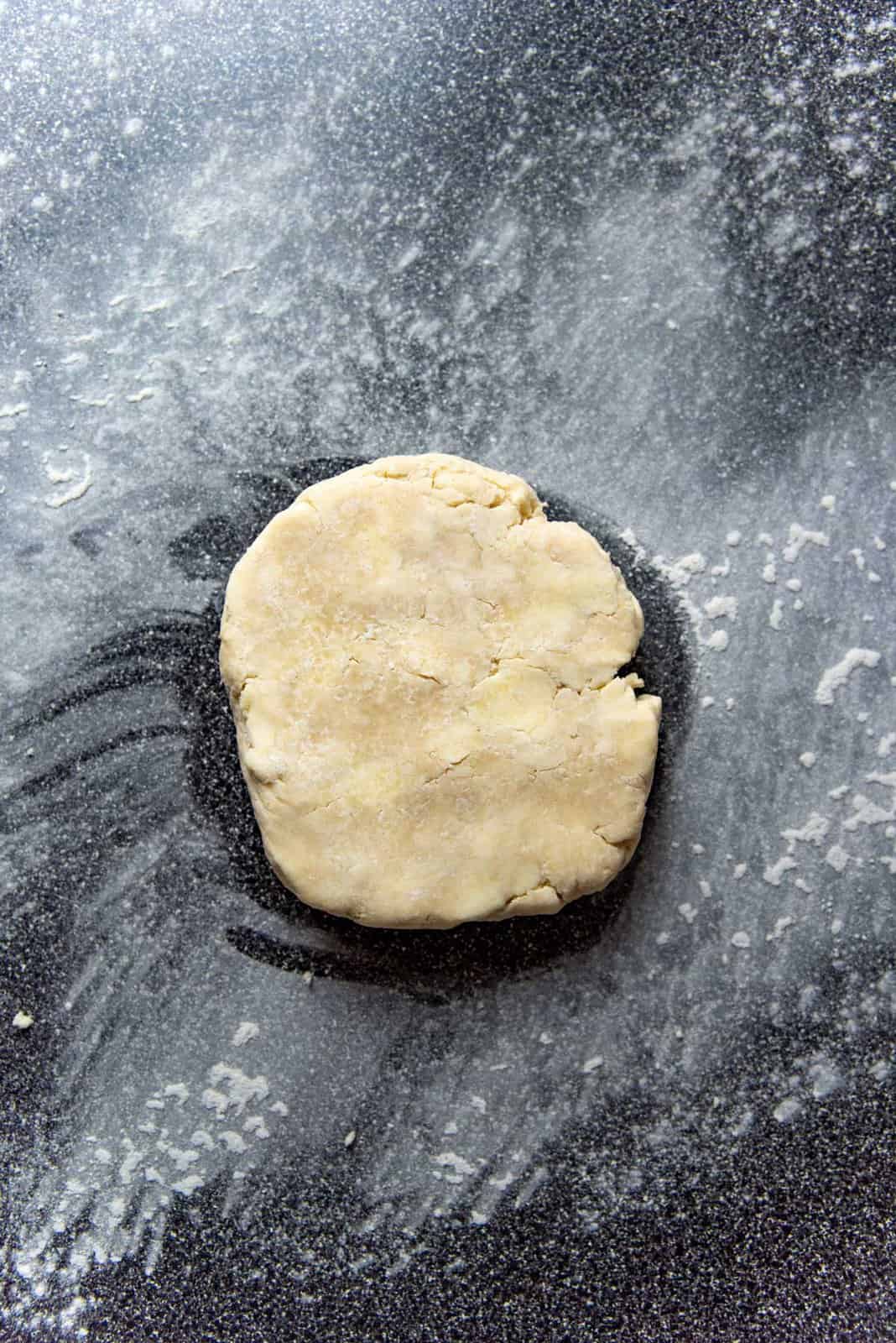 Chilled pie dough disc on a lightly floured surface before rolling it out.
