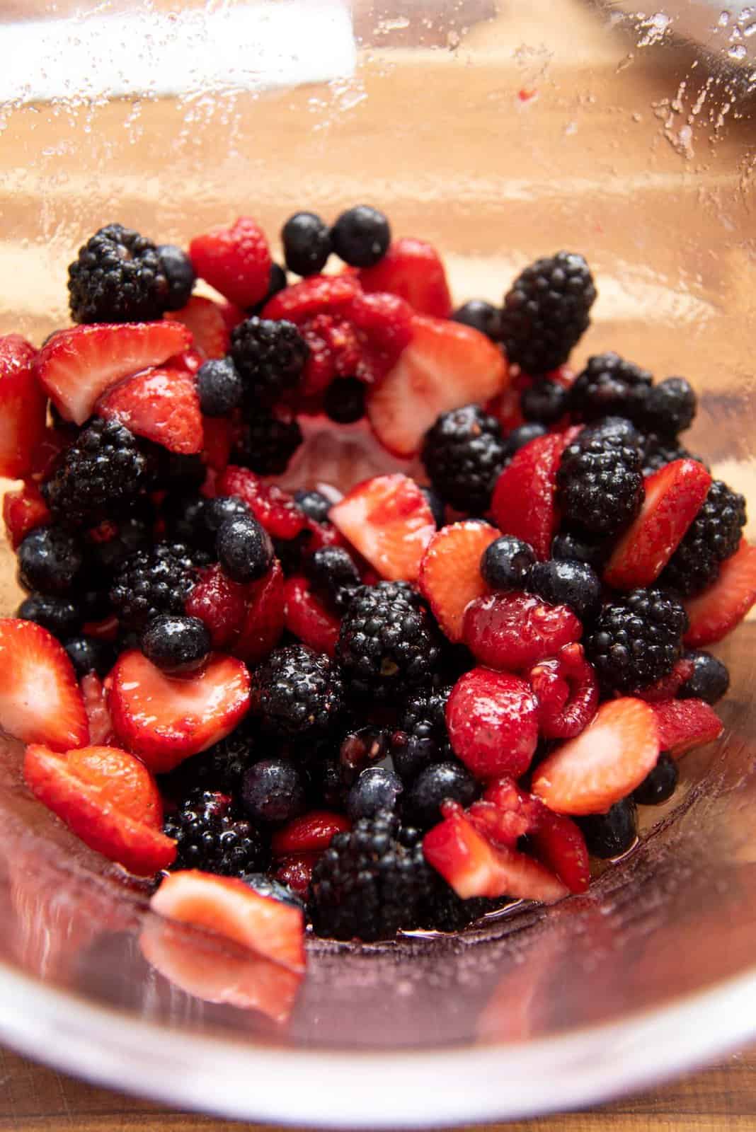 Angled view of mixed berries after being mixed with the sugar.