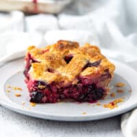 A square image of the mixed berry pie piece on a white and grey plate.