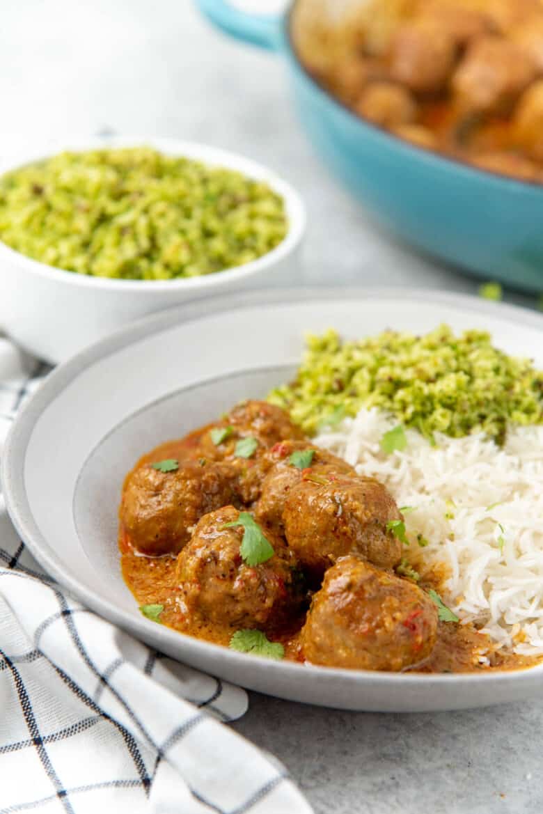A side view of the chicken meatball curry on a plate, served with rice.