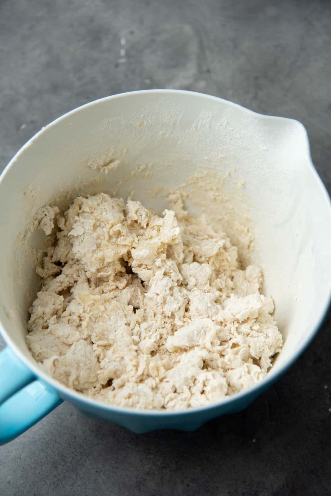 Flour clumps in a bowl, while being mixed with water to form a dough.