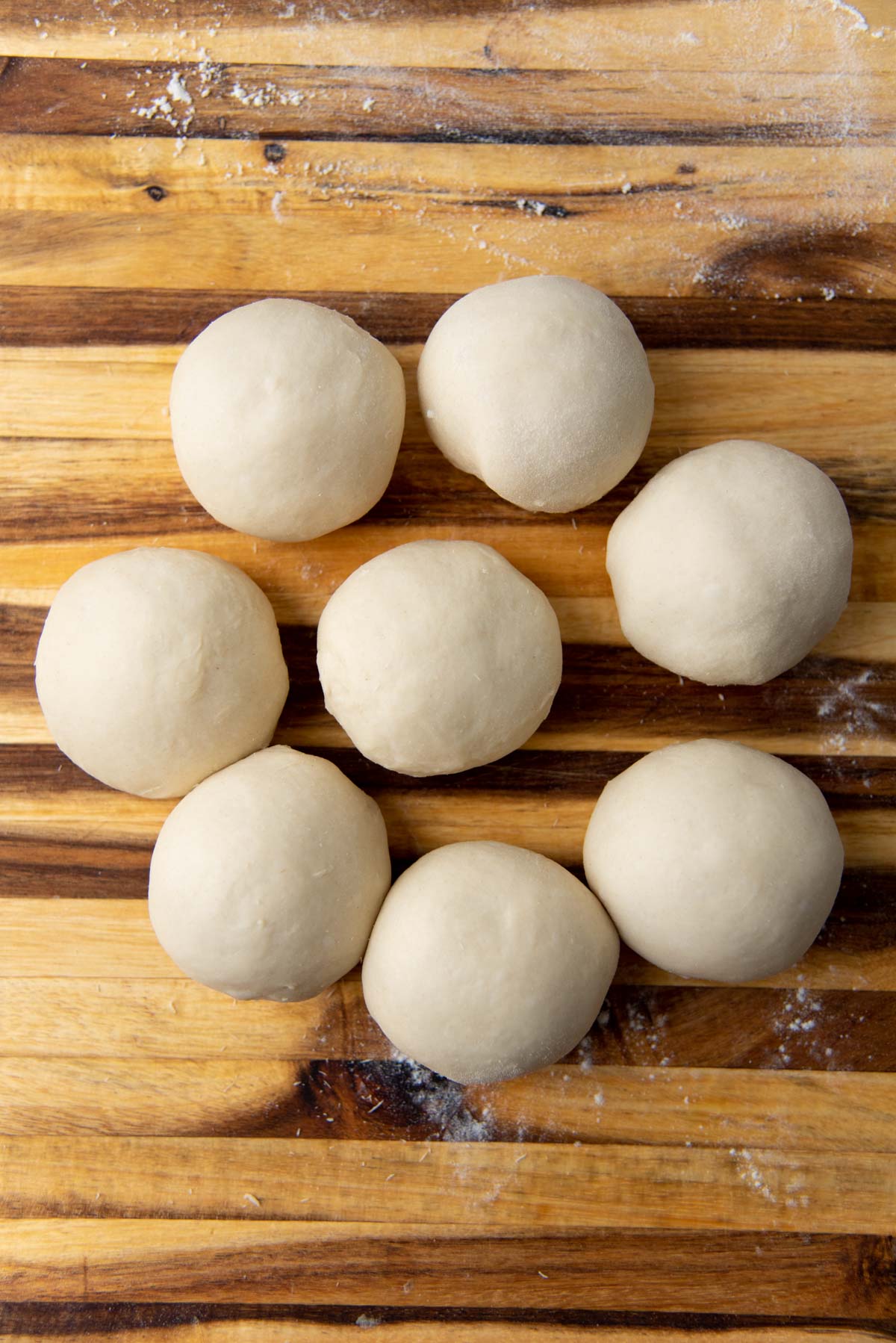 8 smaller portions formed into smooth balls on a wooden board.