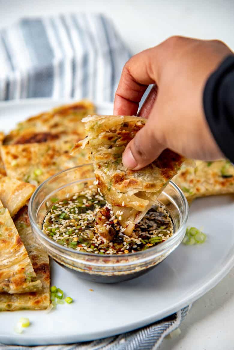 A piece of the scallion flatbread dipped in the sauce.