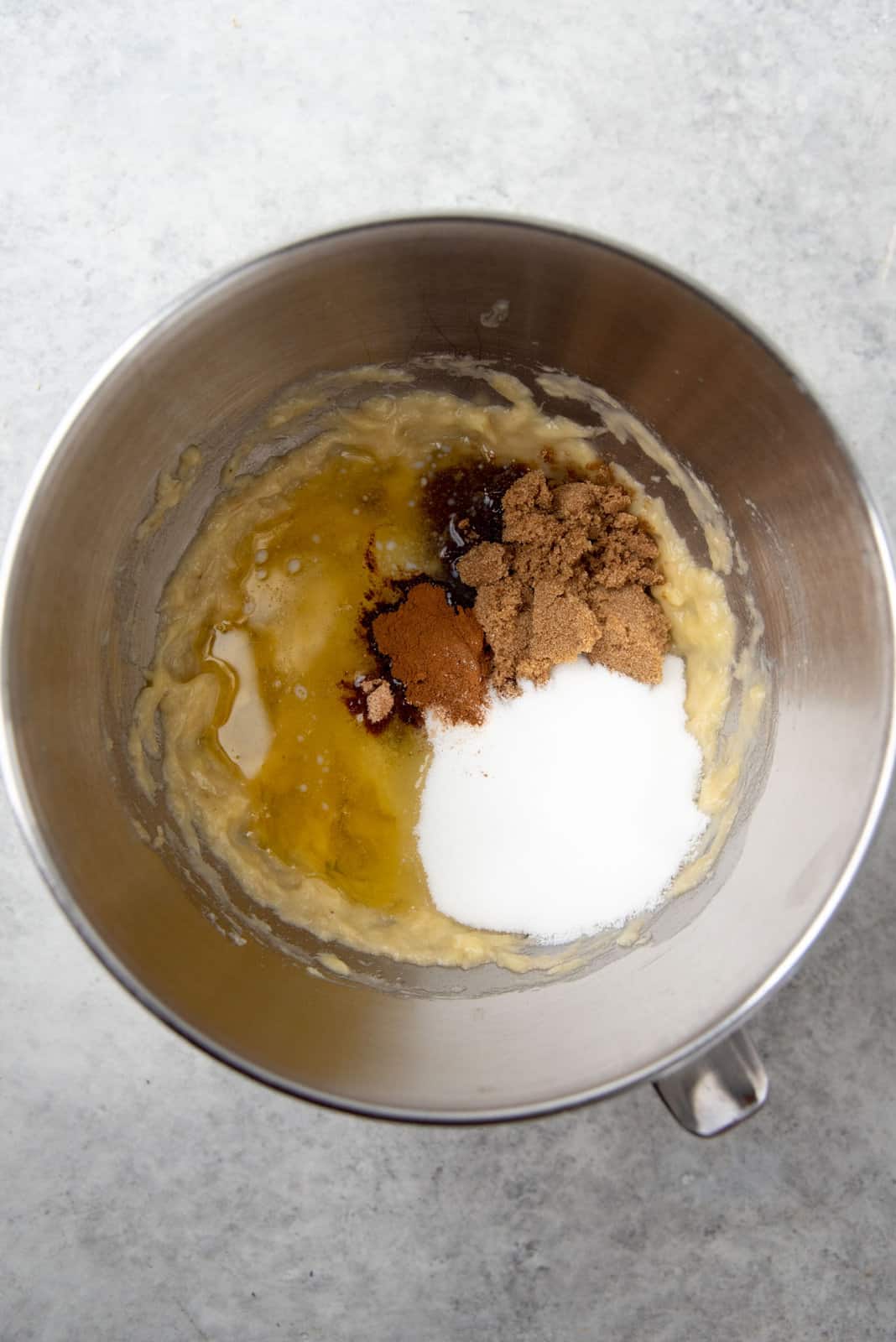 Adding the sugar, fat and flavors into the mashed bananas to make the cake batter.