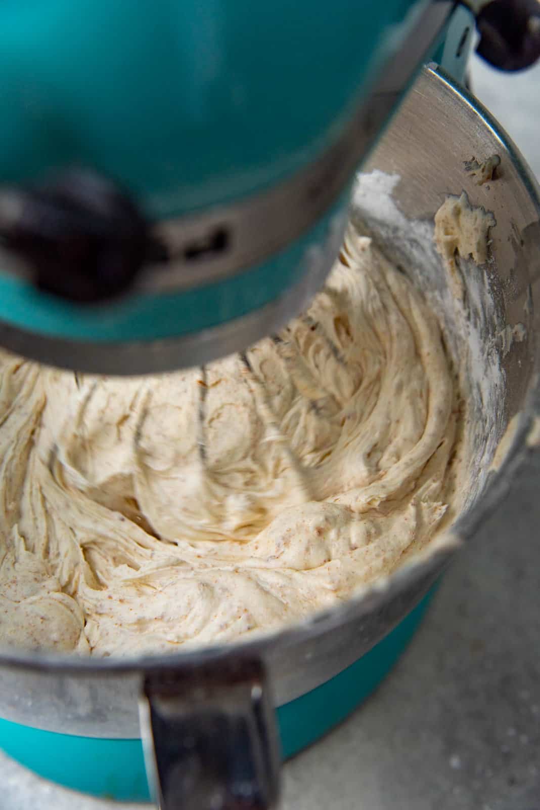 The brown butter cream cheese frosting mixing in a mixing bowl with a whisk attachment.
