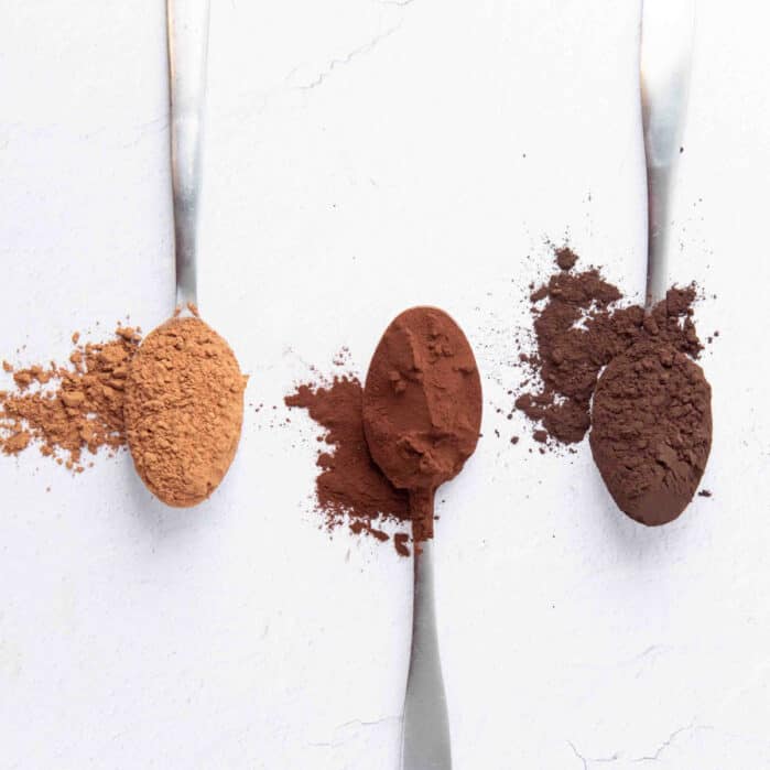 Square image of spoonsfuls of cocoa powder.