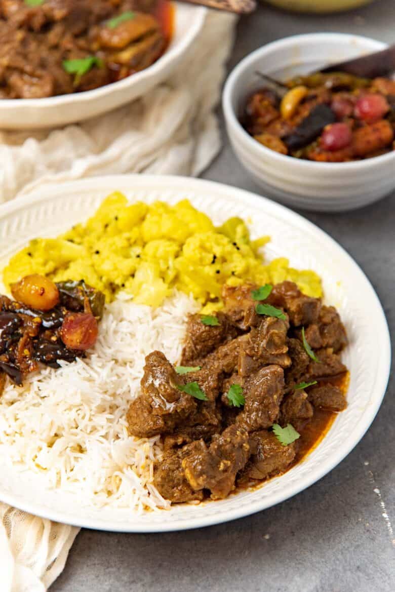 A close up of the Sri Lankan mutton curry served with rice on a plate.