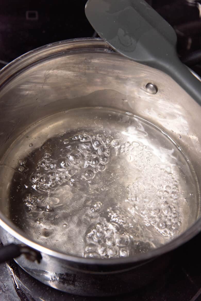 A close up of a pot with water that is boiling rapidly inside the pot.