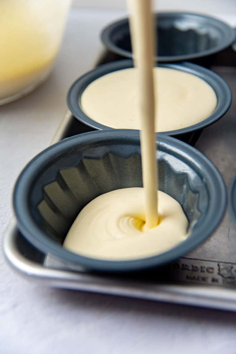 Pouring the custard mixture into fluted dishes to set.