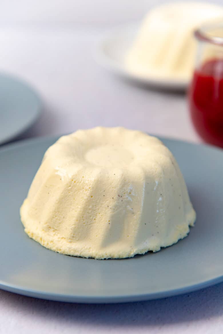 A single white colored, vanilla Bavarian cream pudding, with a bundt pattern, unmolded and served on a blue plate.