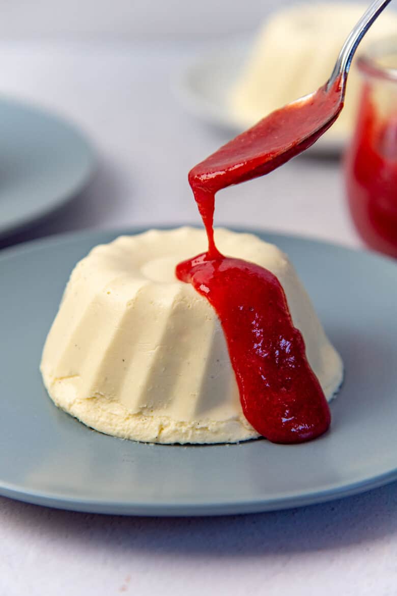 Raspberry sauce being poured ontop of the bavarian cream with a spoon.