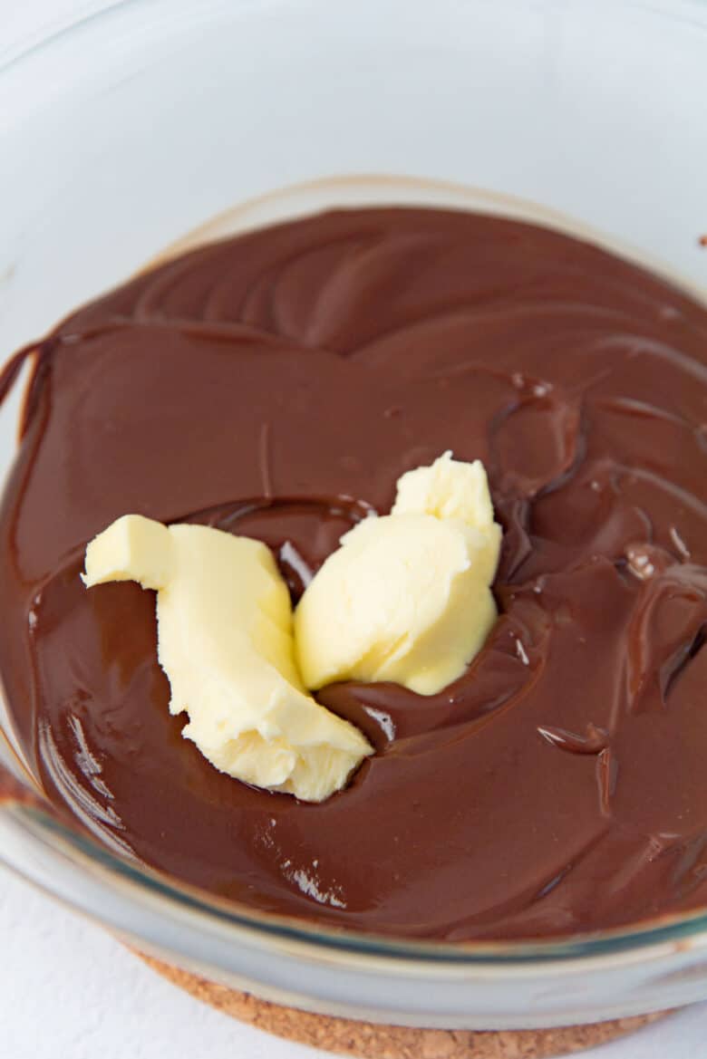 The chocolate cremeux in a bowl with softened butter on top.