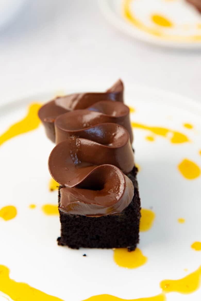 A close up of a chocolate cake with cremeux piped on top. 
