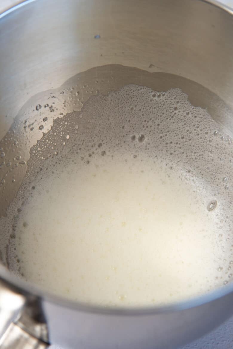 Egg whites whisked to form soft peaks in a metal mixing bowl.