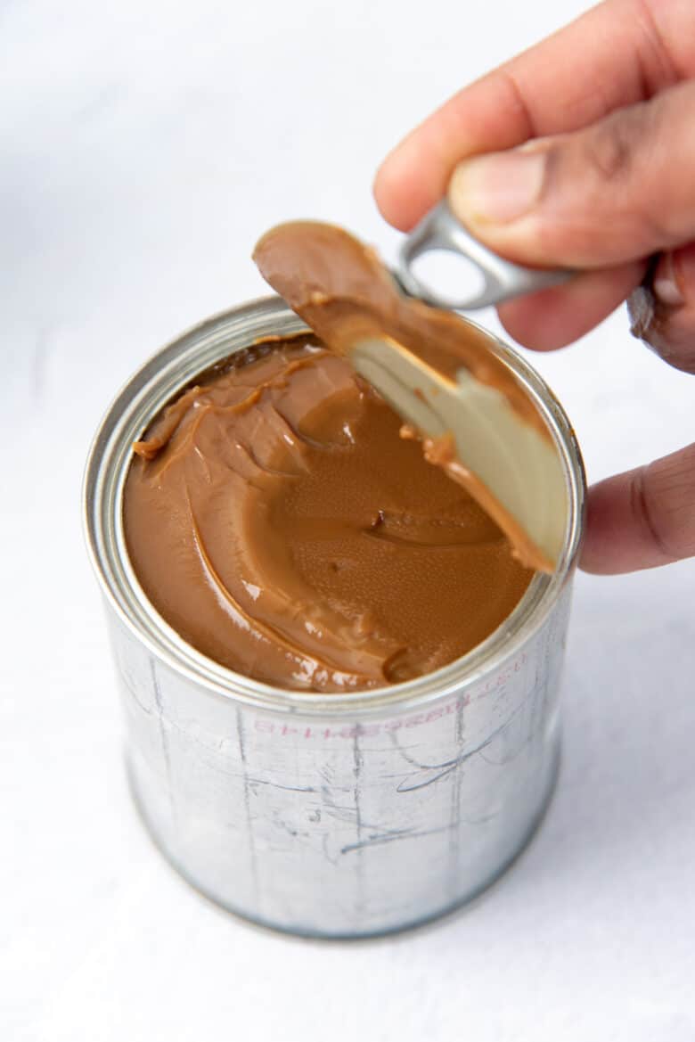 Opening a can of cooked dulce de leche with the tab opening top.