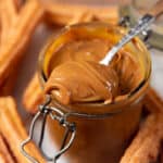 A close up of a spoonful of dulce de leche from a jar of dulce de leche.