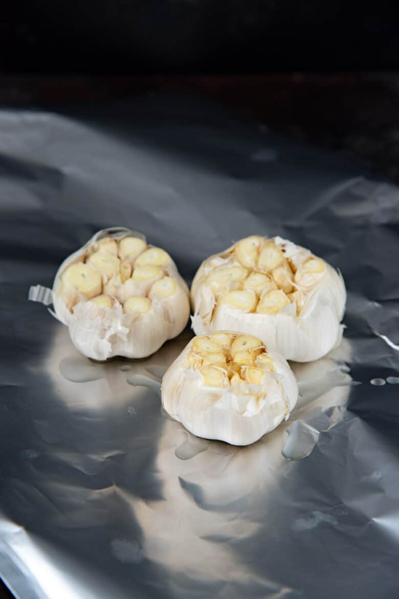 3 bulbs of raw garlic with the tops sliced off, placed on a foil with oil drizzled over. 