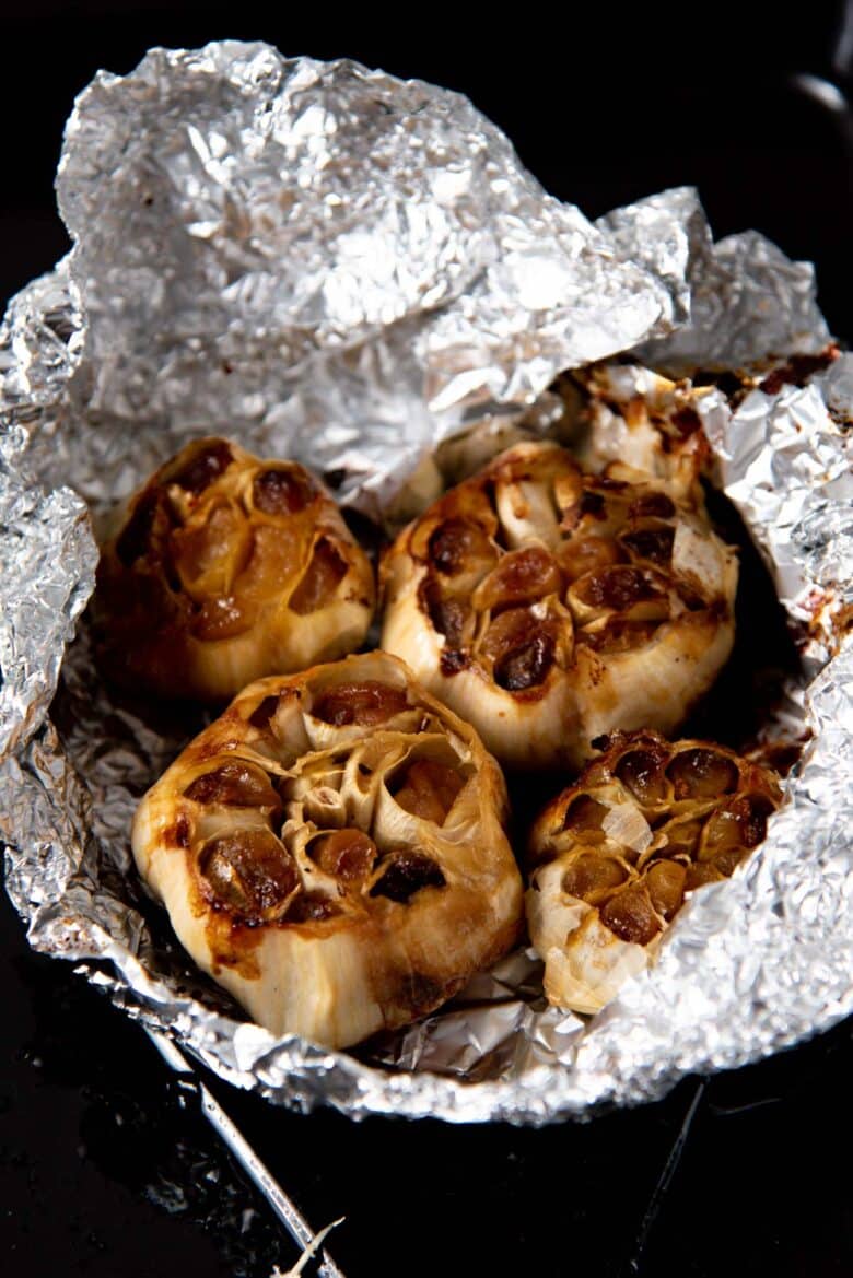 four bulbs of roasted garlic inside a crumpled piece of foil. 