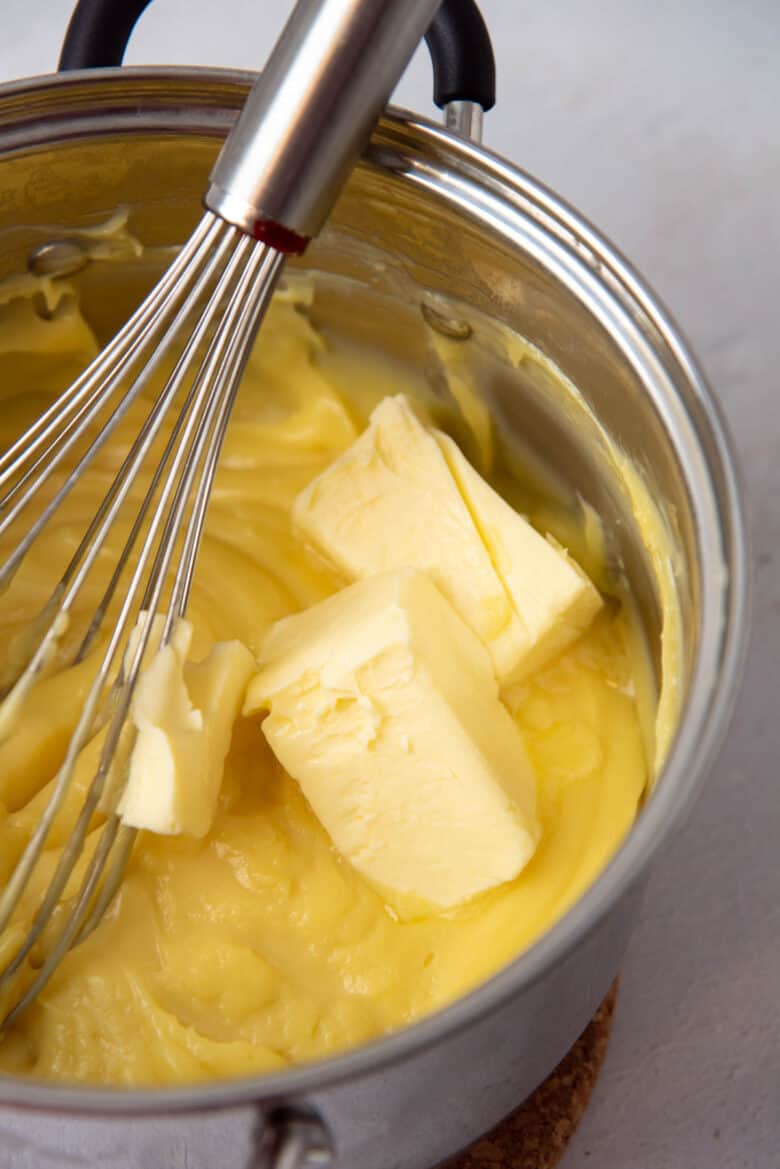 Butter added to the hot pastry cream mixture in a saucepan.