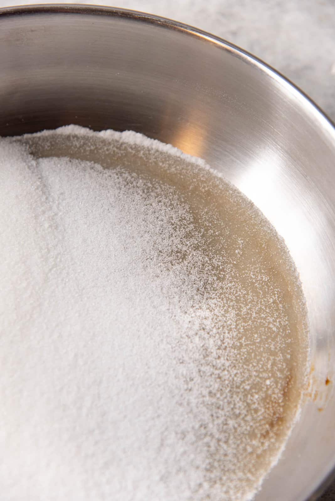 Sugar being cooked in a pan, with the edges melting to form caramel.