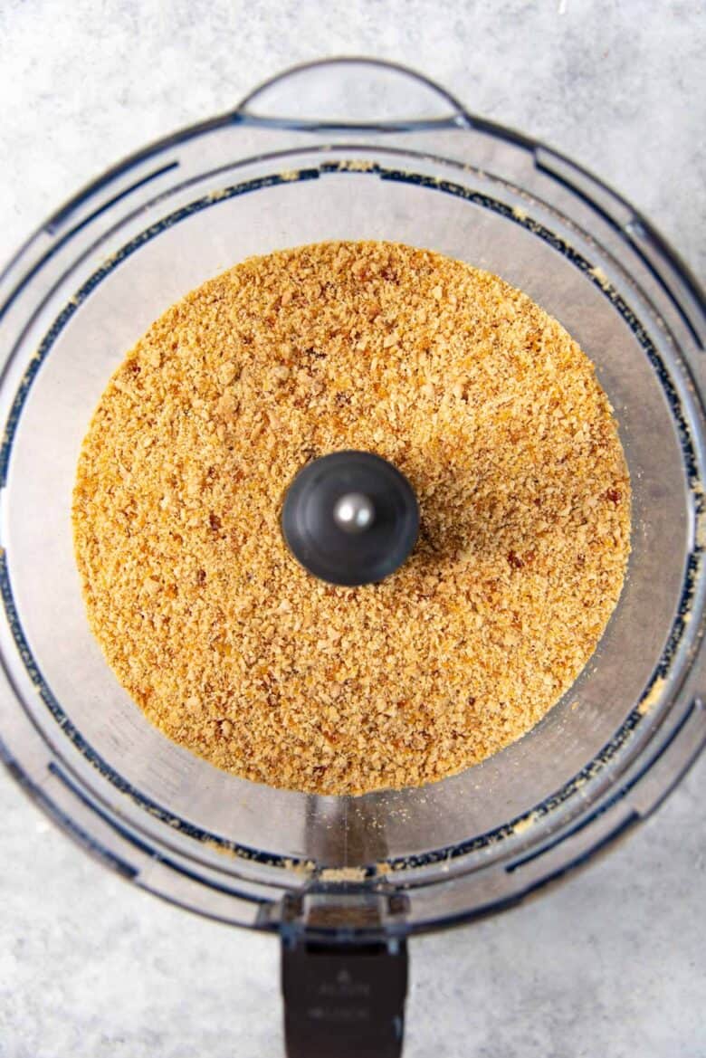 Overhead view of the finely chopped nuts and caramel in the food processor bowl.